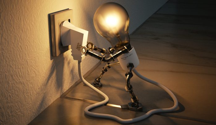 Lit lightbulb man plugging himself into an electric wall socket