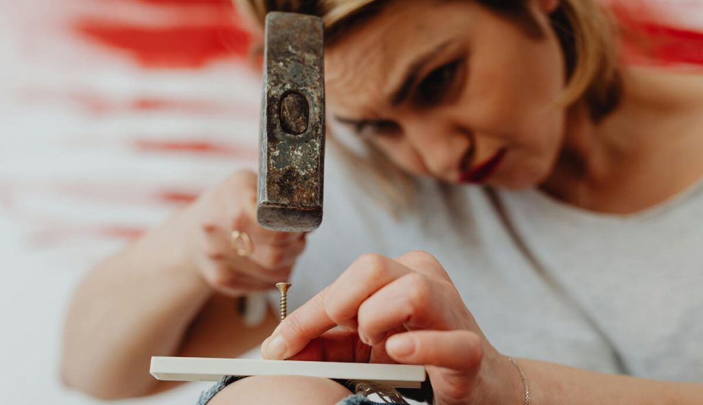 Woman-trying-to-hammer-a-screw-into-a-piece-of-wood