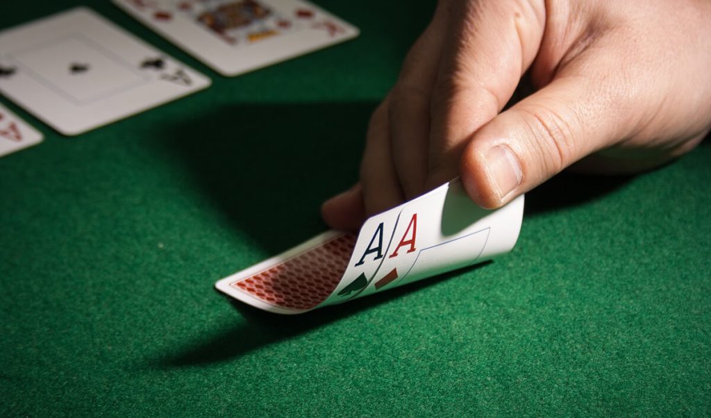 Poker-player-checking-hand-and-finding-two-aces